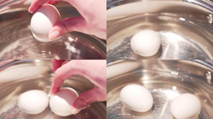在水中煮鸡蛋。女人将白鸡蛋放入水中煮沸，特写慢速