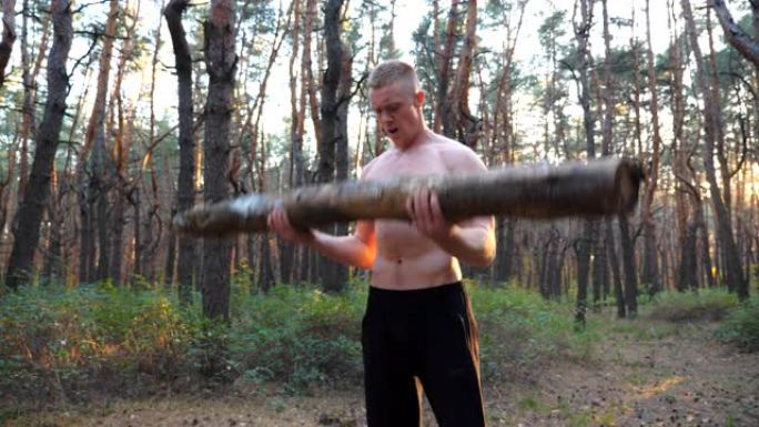 肌肉发达的人举重训练二头肌。强壮强壮的家伙在户外锻炼。运动员在大自然中使用大原木锻炼。运动的概念和积