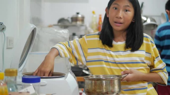 亚洲女孩在家厨房煮饭，女孩帮妈妈准备食物。