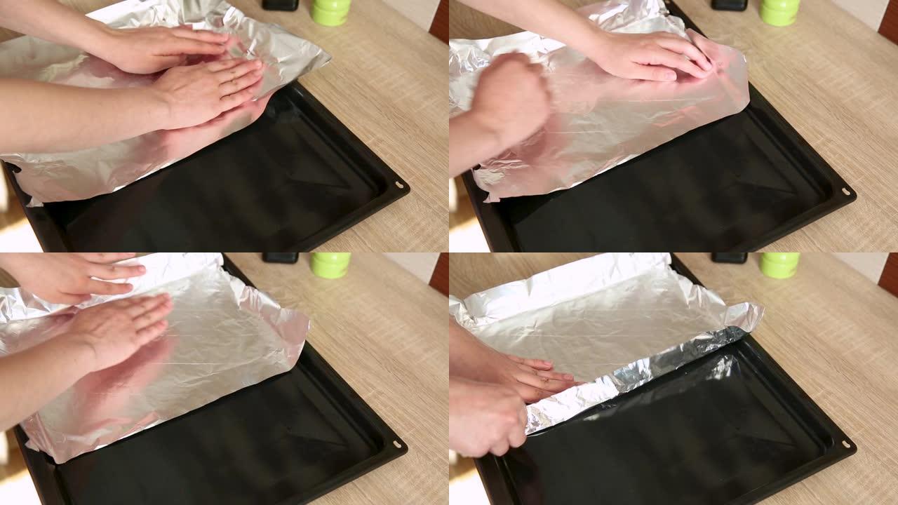 女性手滚动箔纸卷，切成一块，放在烤盘上，以备将来烘烤时使用