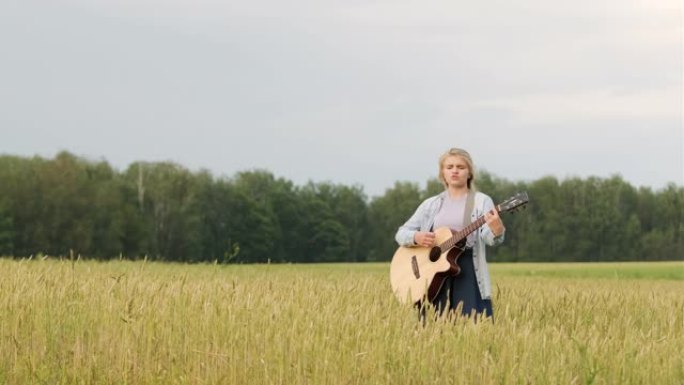 年轻女孩在一个美丽的夏日夜晚日落时在麦田上唱歌和弹吉他