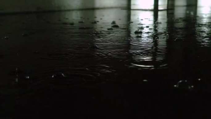 慢动作特写: 秋天的雨水滴落在沥青上的大水坑中，淹没了街道。由于雨季暴雨导致道路洪水。雨滴落在淹没的