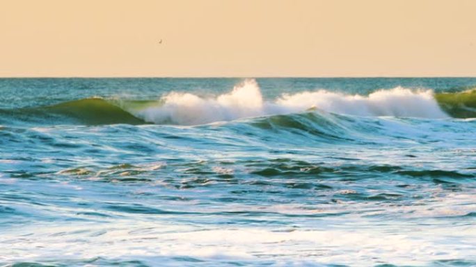 海上日出在滚滚的海浪上朝着海滩