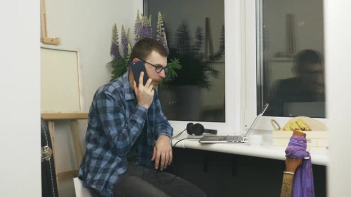 男性自由职业者通过电话与合作伙伴交谈，就新的远程项目达成协议。戴眼镜的男人通过电话与朋友在检疫期间呆