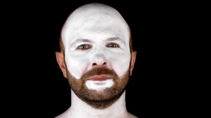 一个脸上有人体艺术的男人。他戴上了白色的剧院面具。