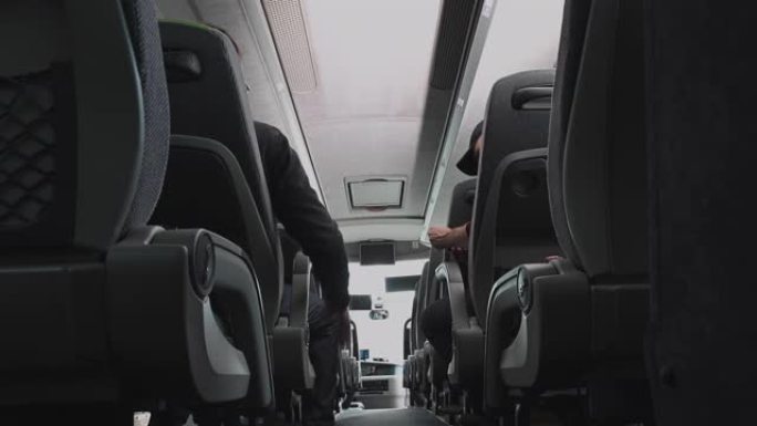 坐在公共汽车上的男性乘客互相交谈调整座位和检查手机。