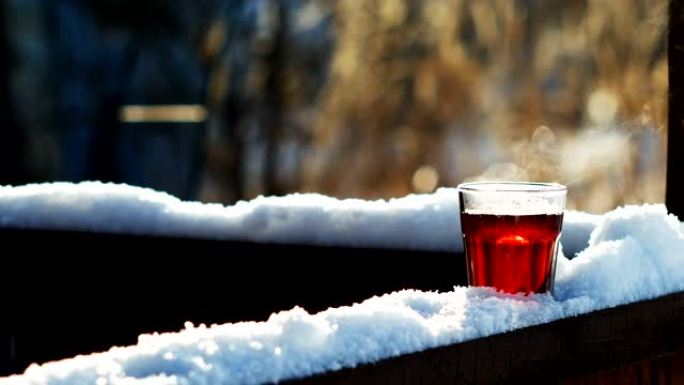 在树枝上站在雪地上的玻璃杯中蒸茶，特写镜头