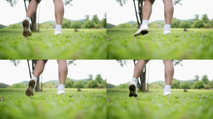 亚洲男性脚踝旋转热身运动在公园低角度看绿草草坪上，脚踝疼痛预防，关节韧带问题，意外事故，腿部小腿肌肉