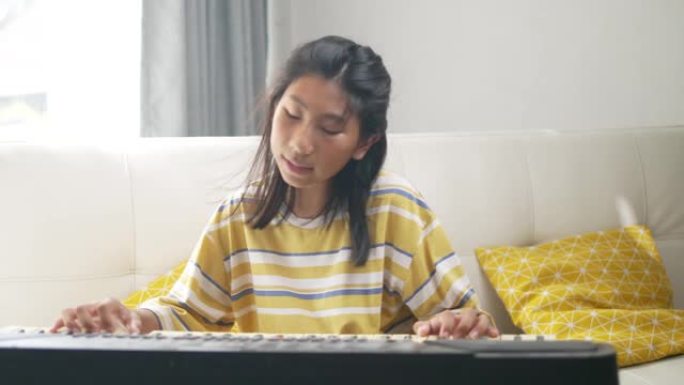 亚洲女孩在家玩窗户附近的键盘乐器，生活方式概念。