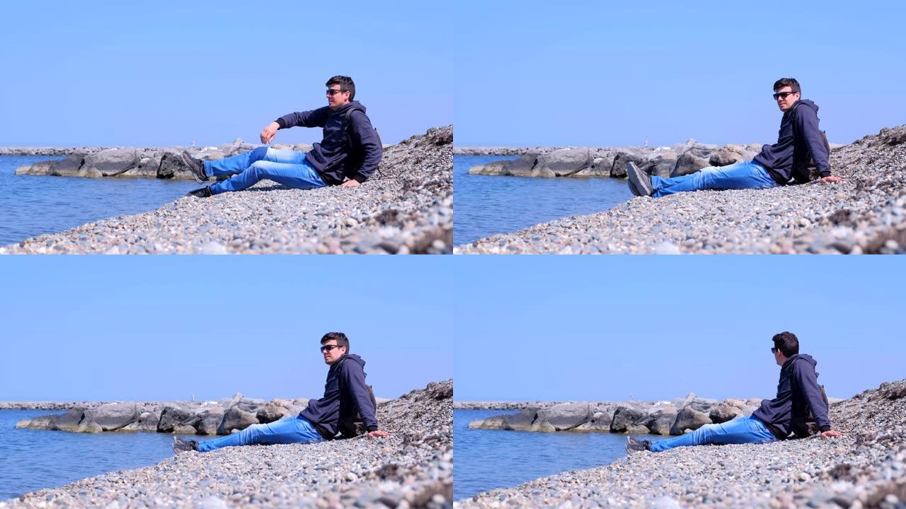 一个旅游旅行者来到石头海滩，看着大海。