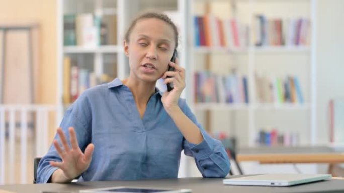 在图书馆的智能手机上生气的非洲妇女