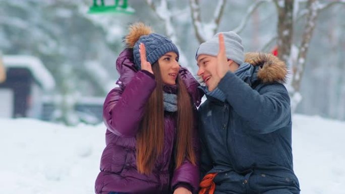 穿着保暖夹克的积极夫妇在雪城公园给了五个