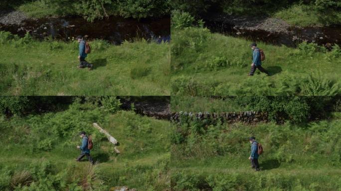 活跃的高级男子在苏格兰西南部偏远农村的一条缓慢流动的小河旁行走