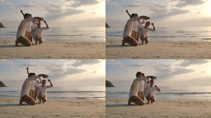 快乐的亚洲家庭在暑假日落时在海滩上玩耍和娱乐。家庭，假期和旅行概念。