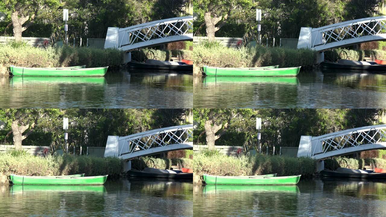一条绿色的划艇被运河中的桥梁绑住