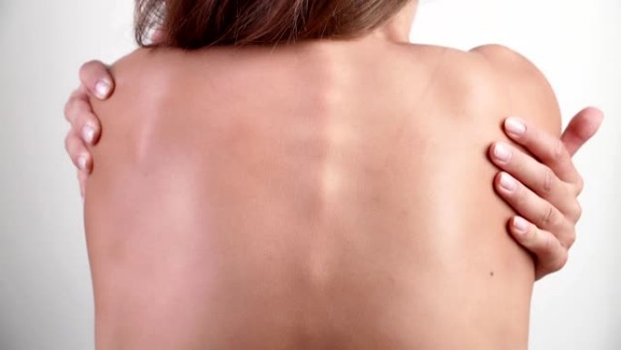 一个美丽苗条的女人痛苦地揉着自己的背。背痛。医疗保健理念
