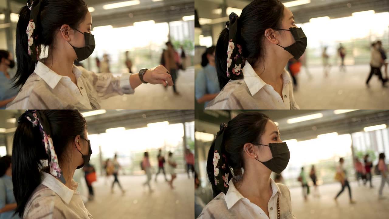年轻的亚洲妇女戴着黑色防护口罩站在地铁应变站内。新型冠状病毒肺炎女士等待朋友，公共交通医疗保健高峰时