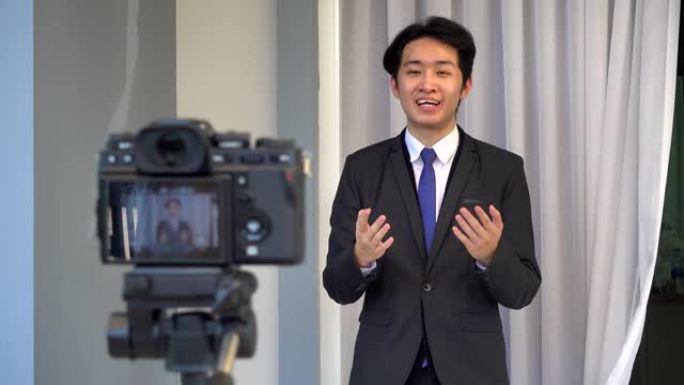 快乐的亚洲年轻英俊的商人在家穿西装，他正在前置摄像头上的视频电话会议，向团队解释或介绍工作