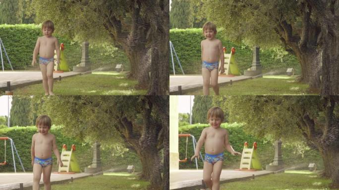 小男孩玩得开心。蹒跚学步的男孩在花园里洒水玩乐的坦率时刻