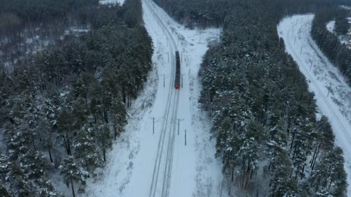 日落时分，通勤火车的空中迎面驶过白雪皑皑的冬季松树林