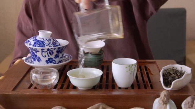 茶师傅在餐具里浇热水的前视图