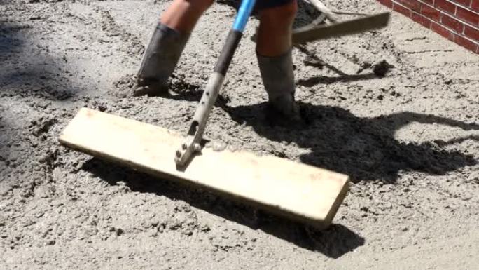 水泥和砂石工人的建筑填充模板用独轮车在混凝土工程中浇注人行道用水泥