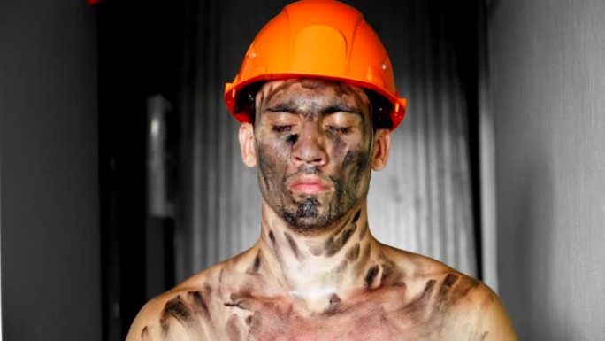 肖像肮脏累了下班后建筑工人在阳光下。戴着安全帽的白人英俊严肃的男人。肮脏的工作和体力劳动。工作设备的