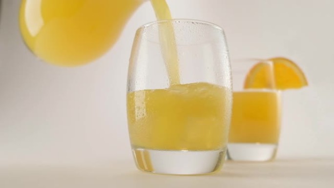 橙汁倒入玻璃和冰块。美丽的果汁浪潮。
