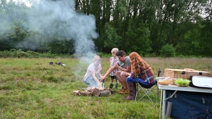 家庭在天然公园的篝火上烧烤食物