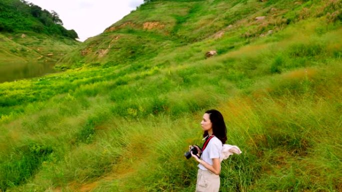 年轻的亚洲女旅行者正在欣赏高山和绿色田野的美丽风景。