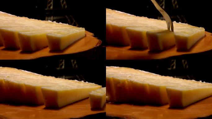 叉子从木板上拿了一块法国硬奶酪
