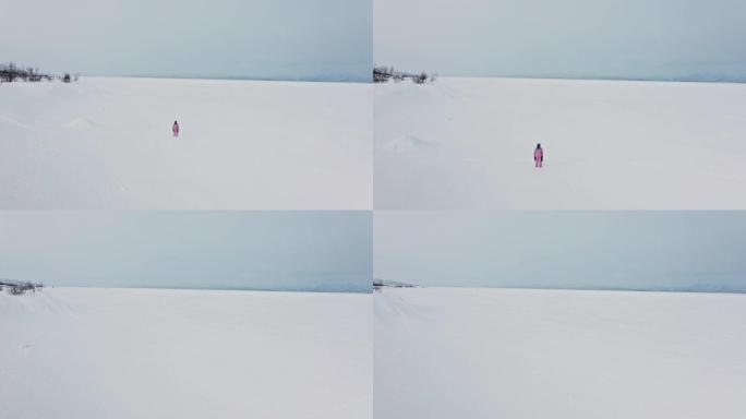 在Abisko瑞典北半球的阴天，单身亚洲妇女在偏远地区行走的冰冻湖tornetr ä sk的无人机镜