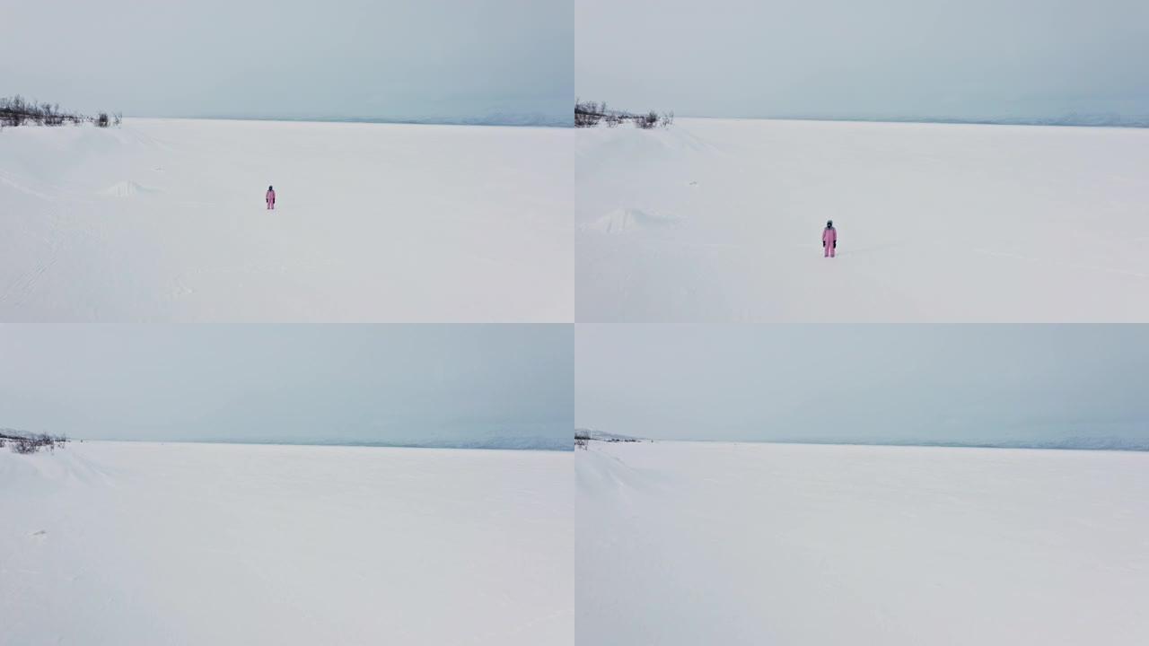 在Abisko瑞典北半球的阴天，单身亚洲妇女在偏远地区行走的冰冻湖tornetr ä sk的无人机镜