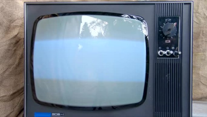 旧电视是用手打开的。发光复古电视屏幕闪烁