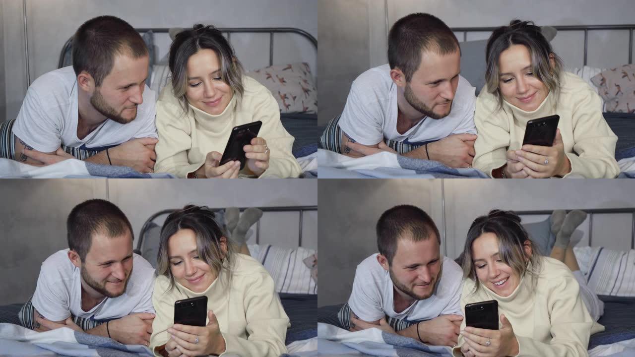 夫妻用手机直播，视频通话到床上的朋友，编织再见。高加索男人和女人。
