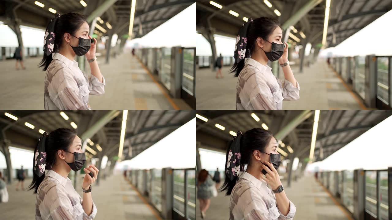 亚洲女性通勤者戴黑色面具站在天空火车平台上，新型冠状病毒肺炎大流行，地铁站内孤独无望的女人新常态，调