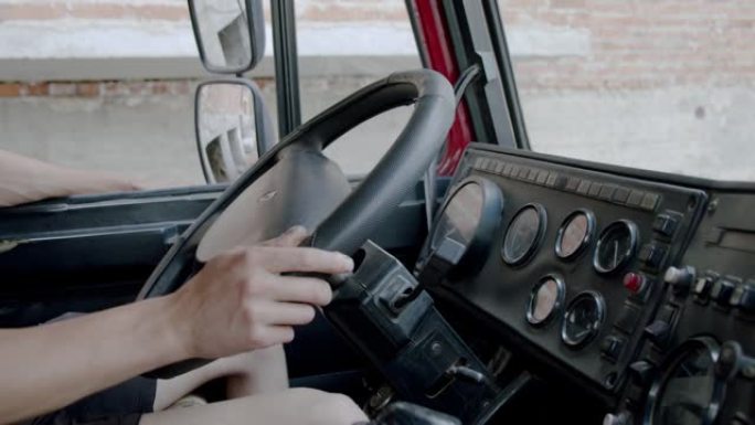 无法辨认的人把手放在方向盘上，从卡车驾驶室驾驶卡车。慢动作特写