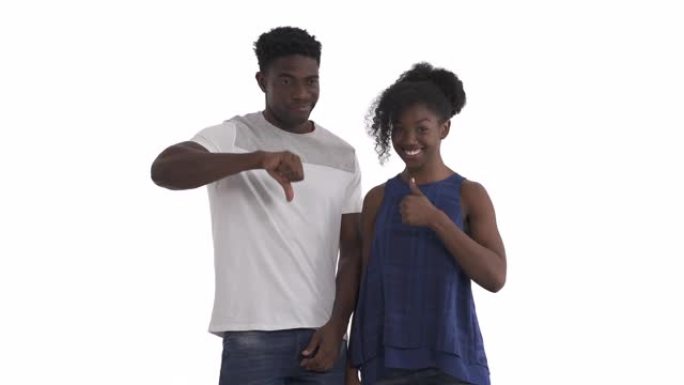 年轻黑人夫妇表达对立情绪的肖像。微笑的女孩竖起大拇指，不满的男人竖起大拇指。孤立在白色背景上