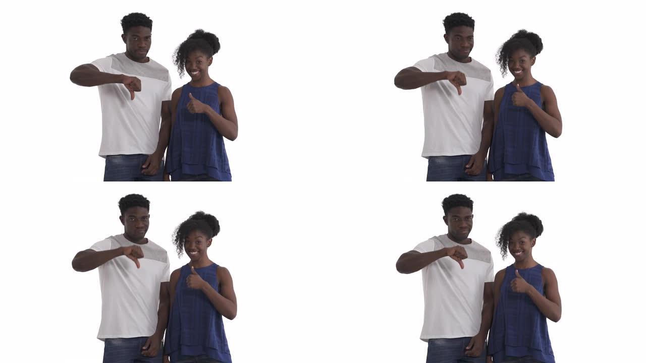 年轻黑人夫妇表达对立情绪的肖像。微笑的女孩竖起大拇指，不满的男人竖起大拇指。孤立在白色背景上