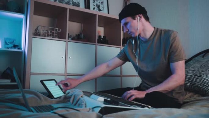 年轻的高加索人坐在卧室里，用MIDI键盘或合成器演奏，制作电子音乐。Dj慢动作镜头
