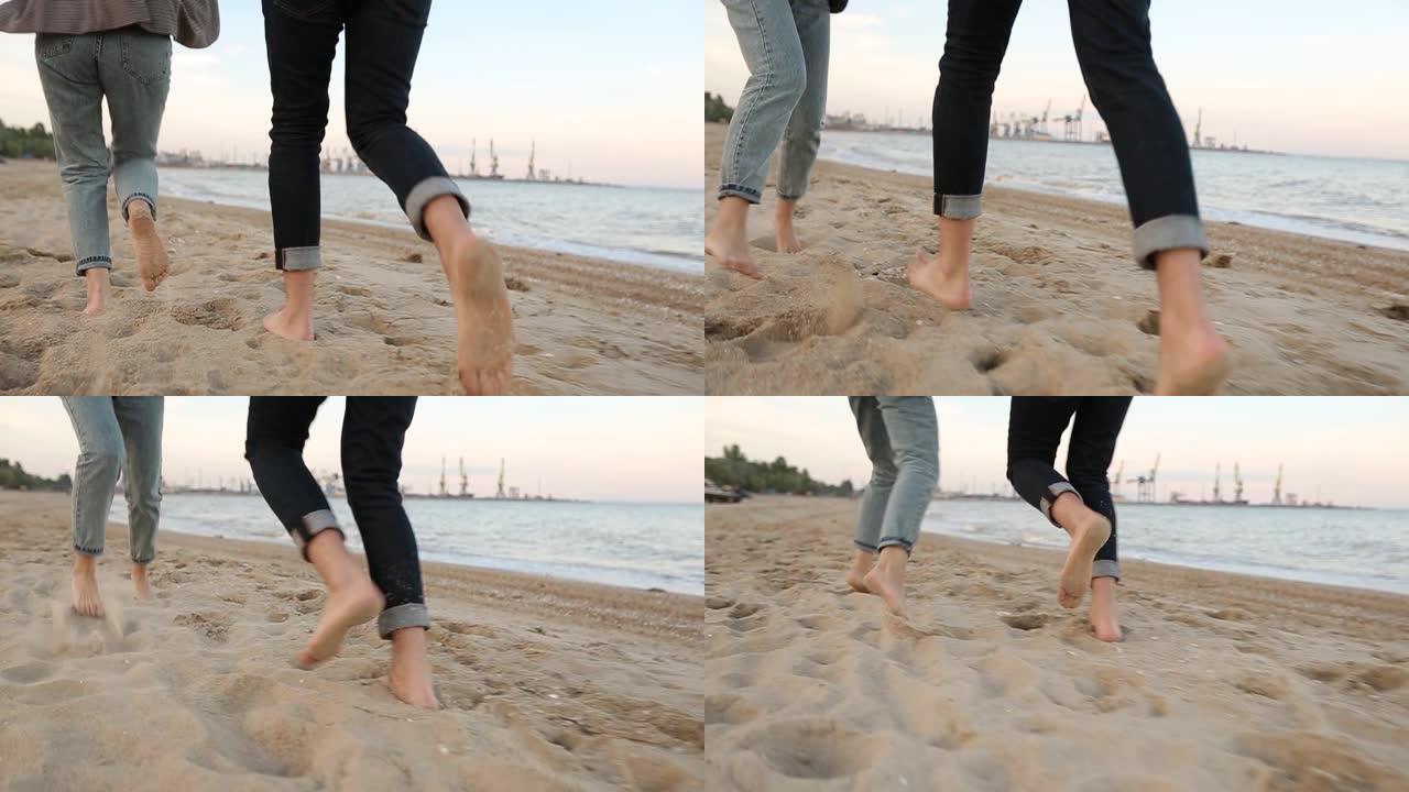 在海边的海滩上慢动作，浪漫的情侣脚在沙滩上奔跑，向后低角度的视图。男朋友和女朋友在海边玩得开心。恋爱