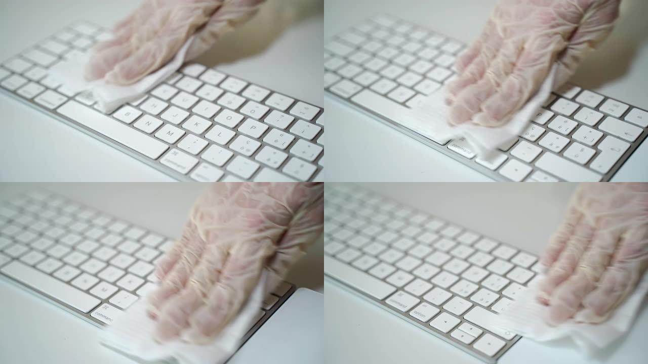 戴着白色防护手套的人使用湿抗菌擦拭并清除键盘表面的脏污，微生物和细菌。新型冠状病毒肺炎大流行期间的卫