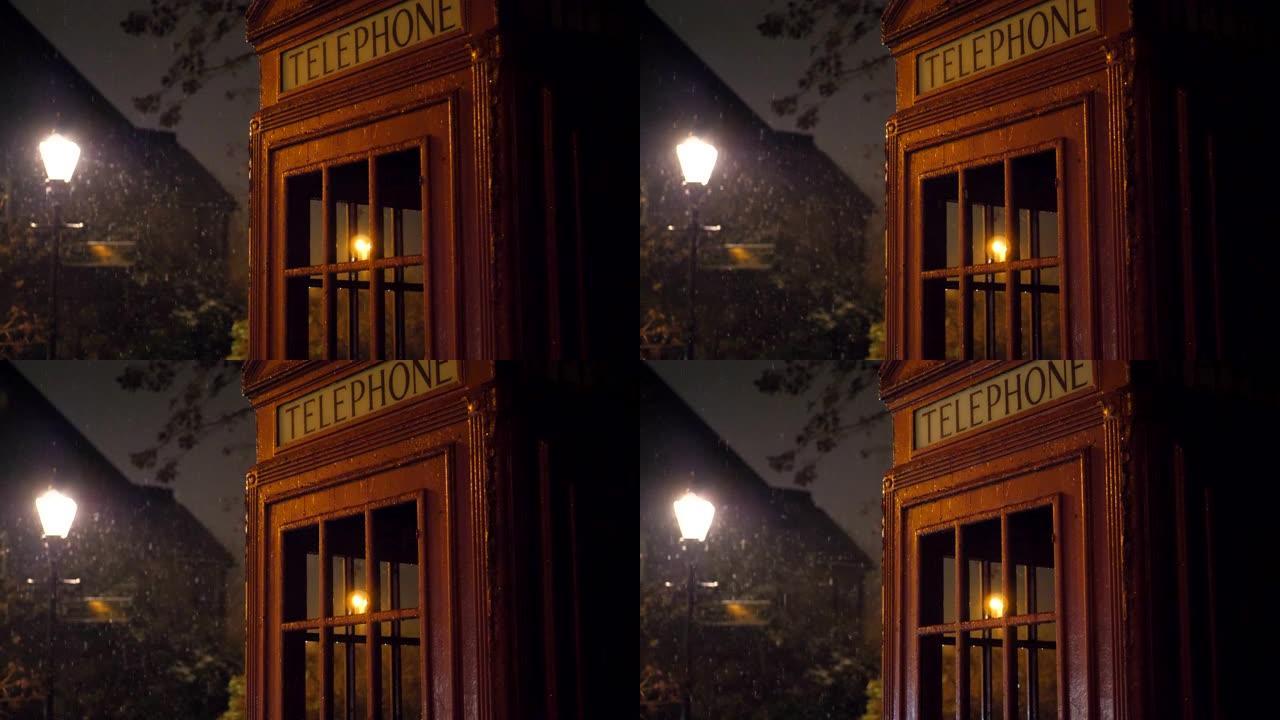 雪落在红色的电话亭和夜晚的街灯上。