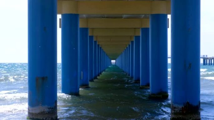 平行的蓝色圆柱之间的码头下的海，在水中形成狭窄的走廊。