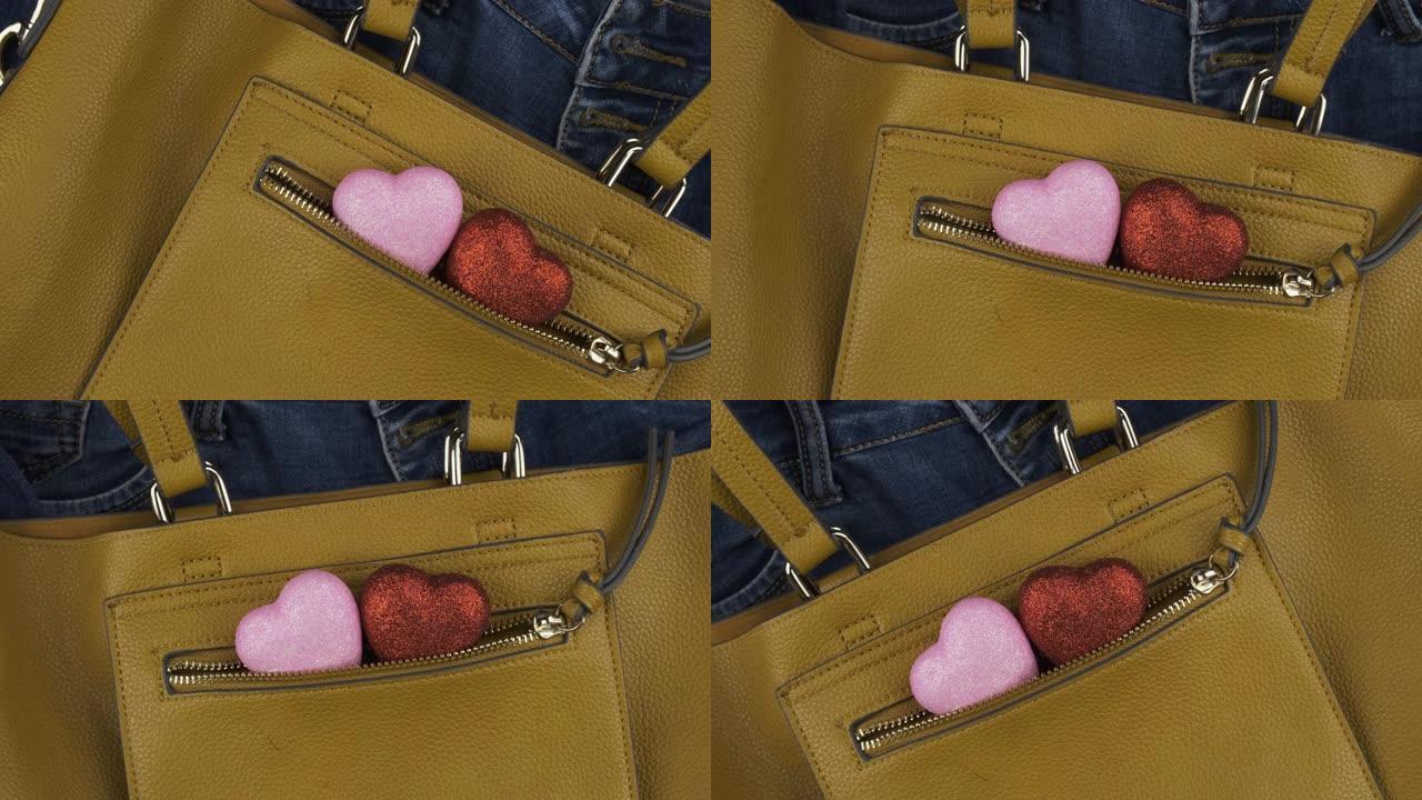两个心脏从一个女性黄色包的口袋里伸出来。轮动。爱情和时尚的背景。