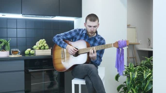 男人在家练习用原声吉他弹奏和弦。专业音乐家弹吉他和唱歌。吉他手在家中独奏，并在情感上演唱抒情歌