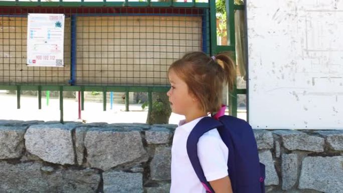 一个戴着蓝色背包的金发小女孩上学。学校概念。