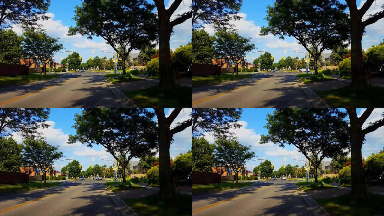 骑自行车的人在夏天穿过城市郊区的灯光路口。骑自行车的人白天驾驶城市郊区的车辆穿过红绿灯路口。