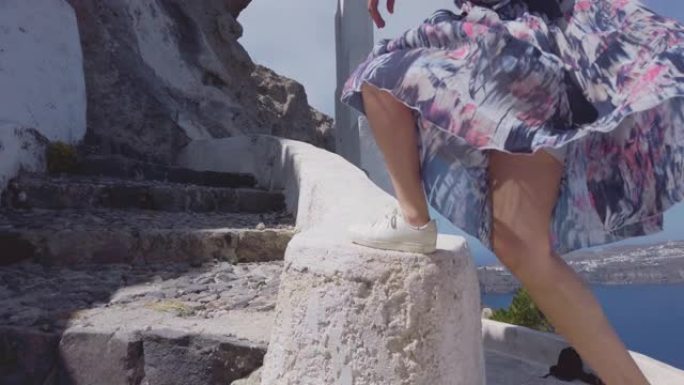 穿着裙子的女人走在圣托里尼岛中心和圣托里尼岛Agios Nikolaos东正教教堂的楼梯上，慢动作