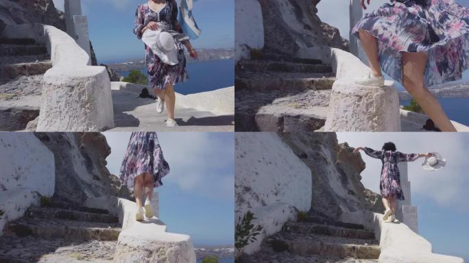 穿着裙子的女人走在圣托里尼岛中心和圣托里尼岛Agios Nikolaos东正教教堂的楼梯上，慢动作